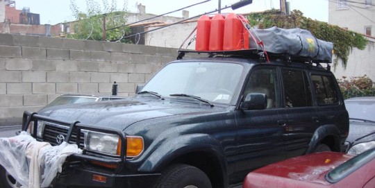The folded roof tent on the right and gas cans to extend the range of the gas-guzzler Toyota.
